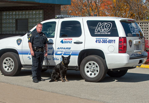Sgt. Hartman and his police dog 'Honz' standing next to a police vehicle.