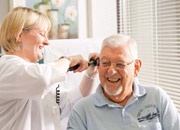 Senior man smiling as a nurse checks his ear