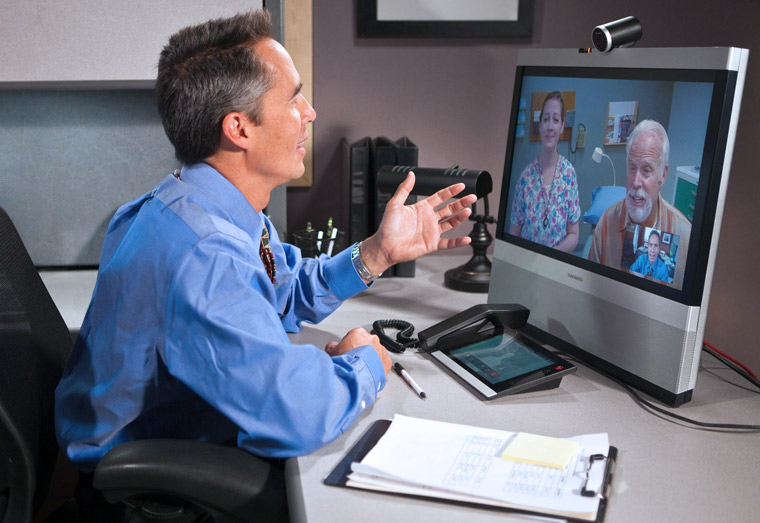 A Veteran consults with a physician from his office using telehealth equipment.