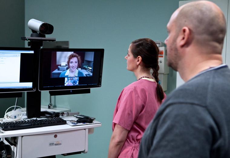 During a clinic visit, a Veteran and a nurse interact with a provider via telehealth.