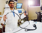 A physician standing in a treatment room holding up an endoscope.