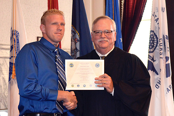 A judge presents a certificate to a Veteran who graduated from the treatment court.