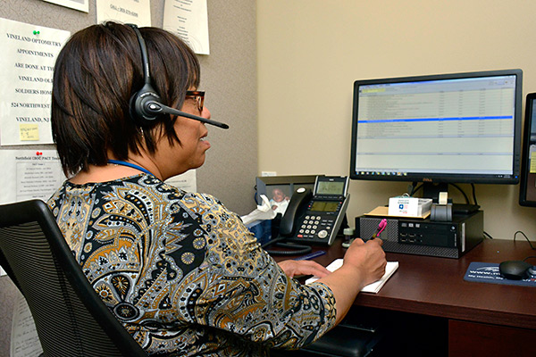 A woman talking on a phone headset with a patient.