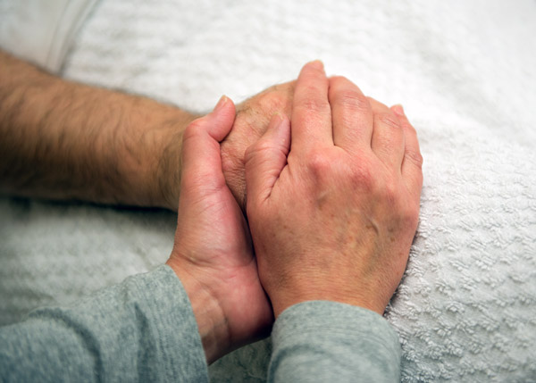 Close of of a caregiver holding a patient's hand.