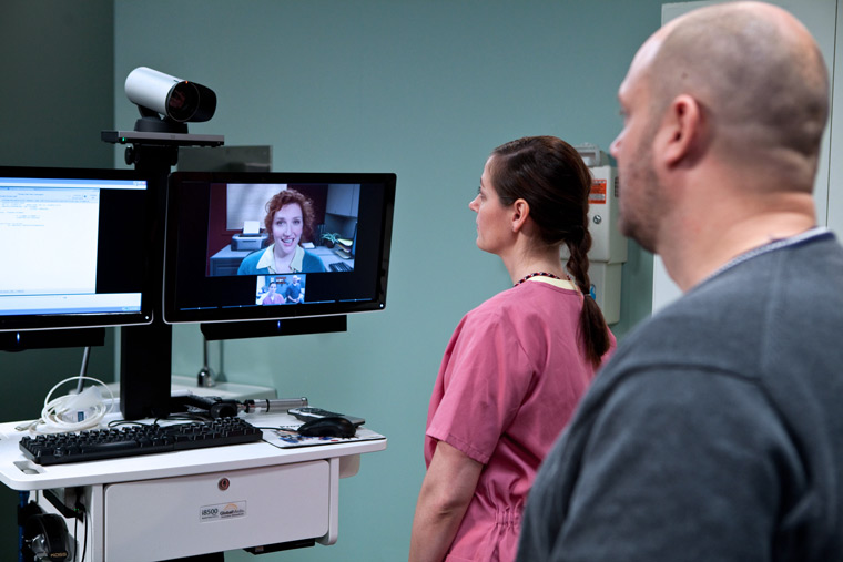 A veteran and a nursing assistant interact with a provider via telehealth during a clinic visit.