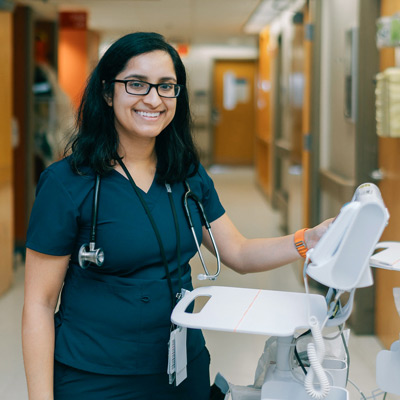 A smiling nurse standing in a hospital hallway.