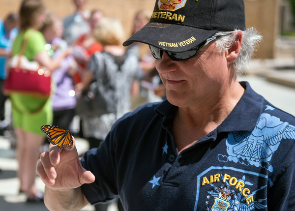 A Veteran holding a butterfly on his fingertip.
